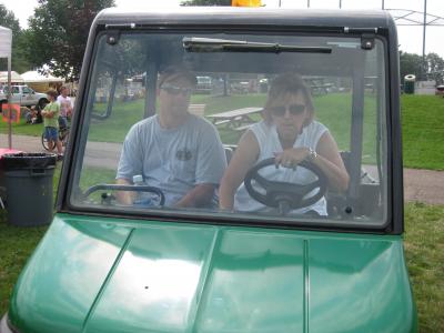 2 individuals in a golf cart overseeing community day events.