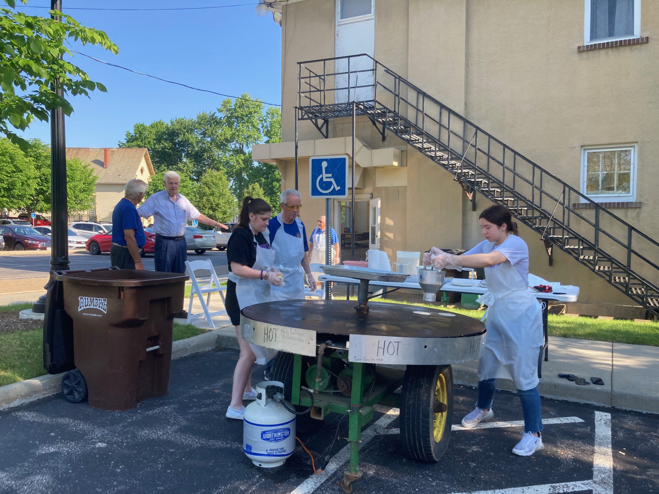 Group of volunteers cooking pancakes on a large griddle.